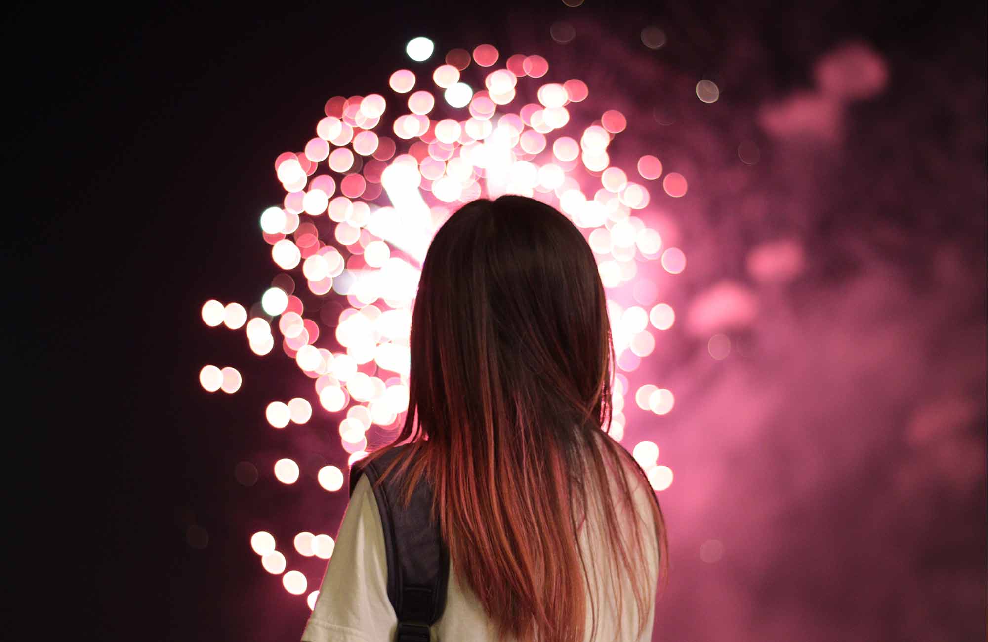 Kona að horfa á bleikan flugeld springa í desember