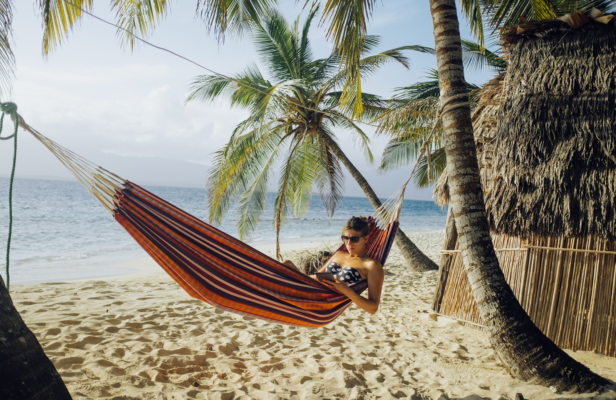 a student in a travelling classroom in a hammock on the beach