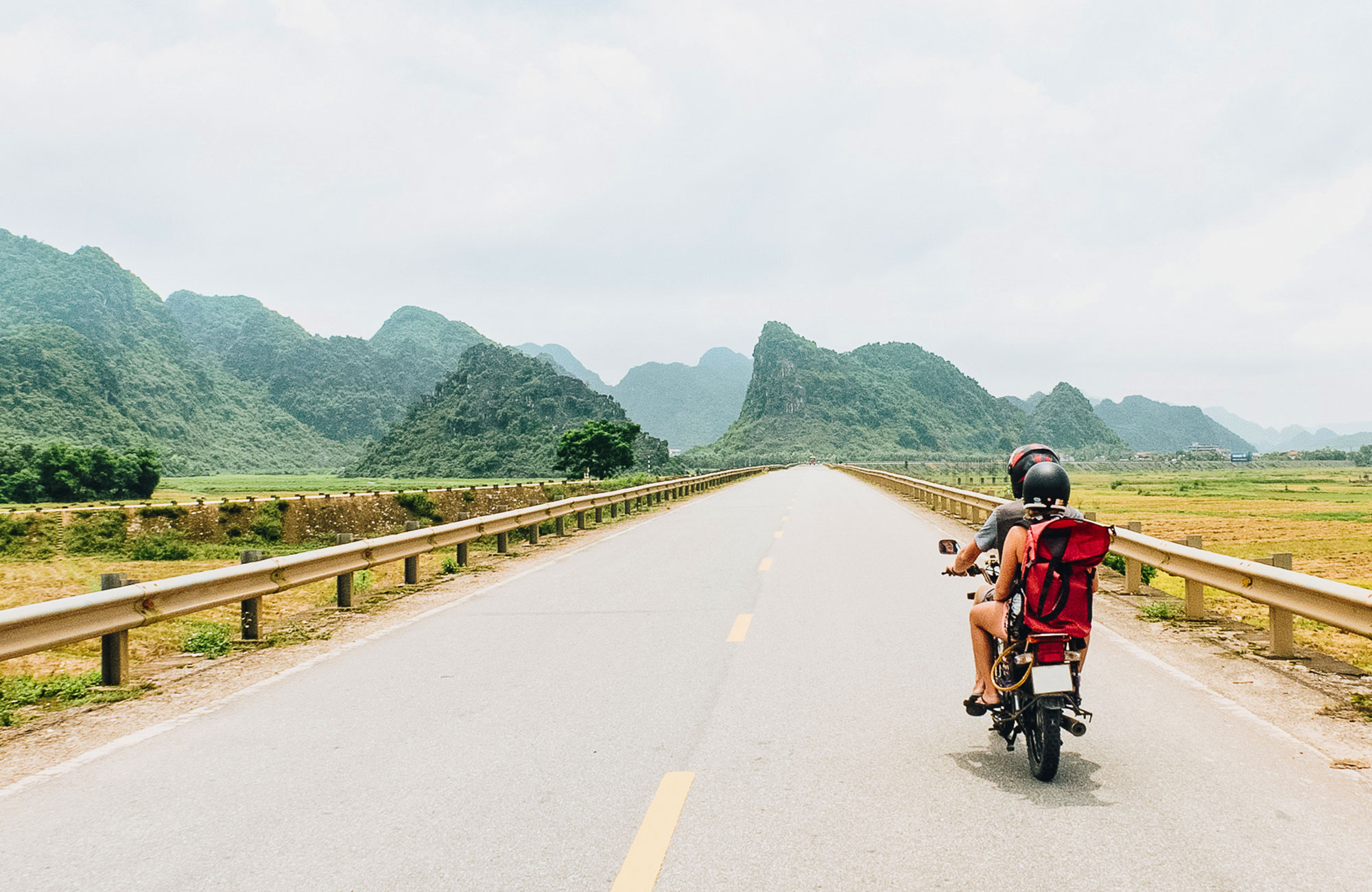 Travellers on a motorbike on an empty road in Vietnam