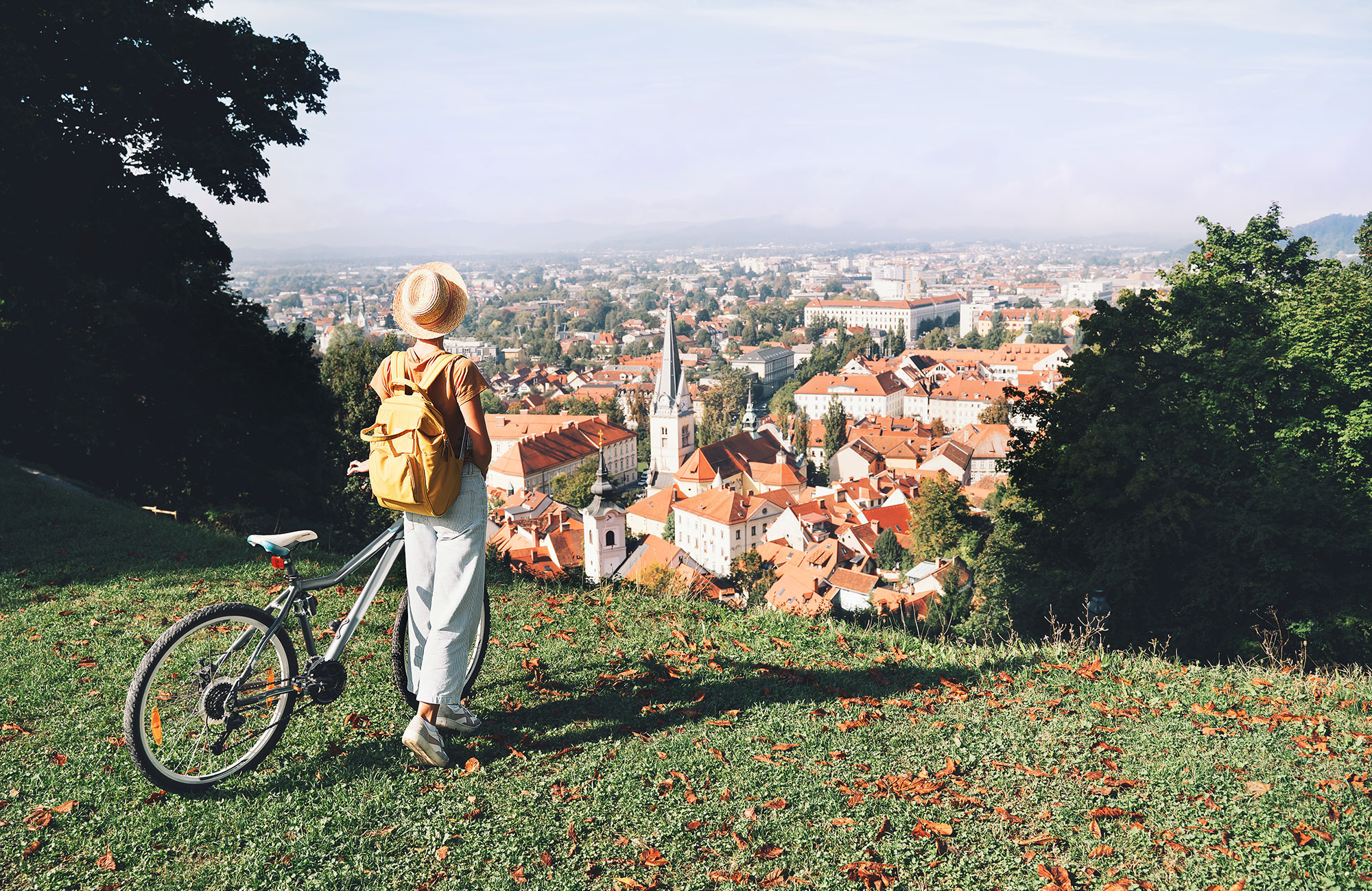 manneskja í ljubljana stendur á móti sólinni með útbaðaða handleggina á meðan hún er í road tripi í slóveníu