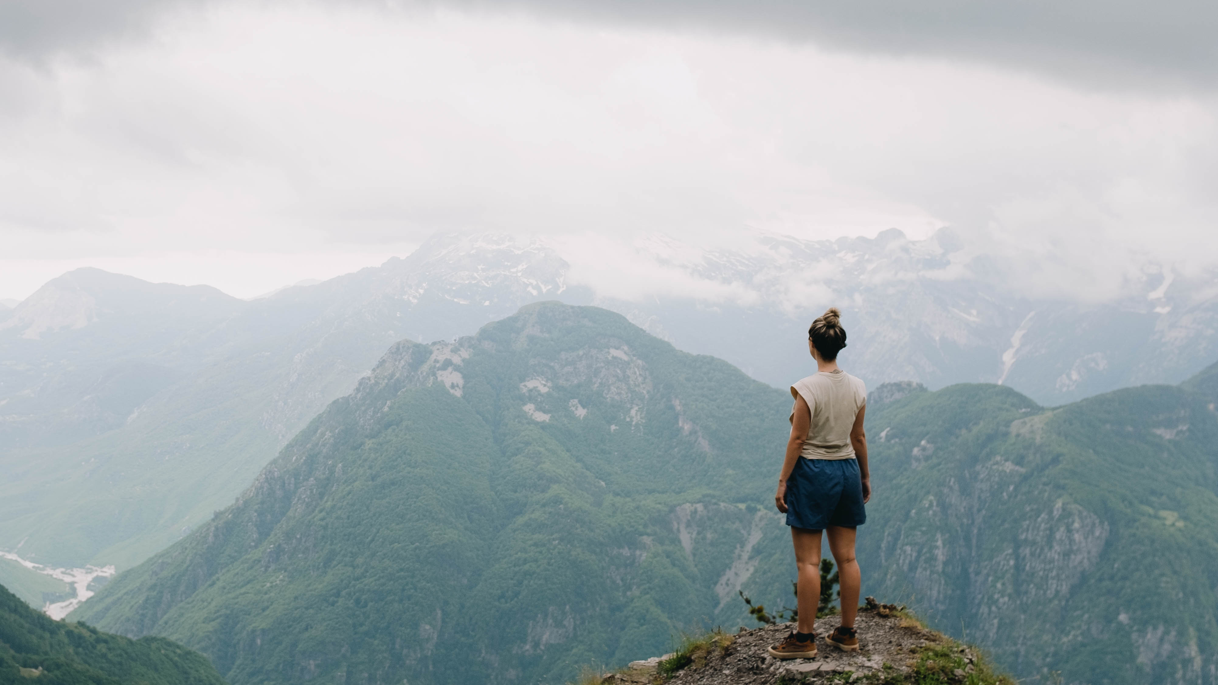 Girl standing on a mountaintop overlooking a mountainous view in the Balkans